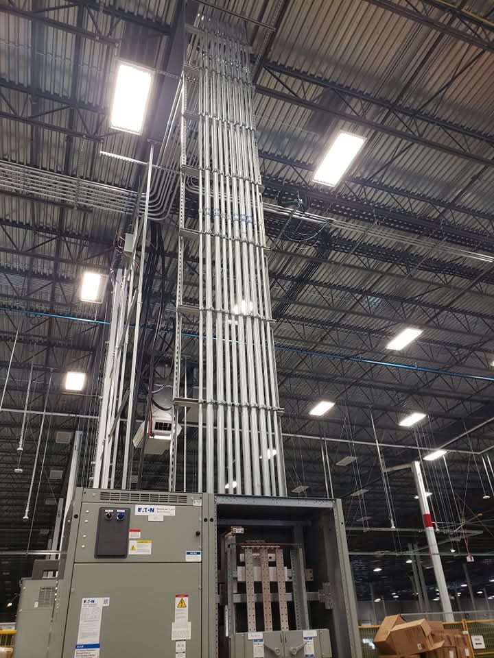 Vertical conduit run rising up to the ceiling of a large industrial space